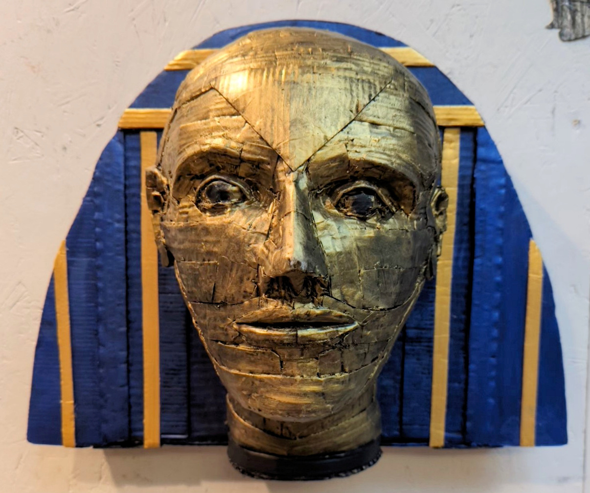 Gold face with headdress sculpture